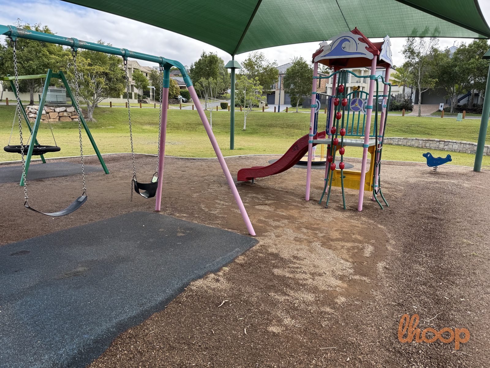 A swing set with a toddler seat, the red slide tower and a blue bird spring rocker on the soft playground base.