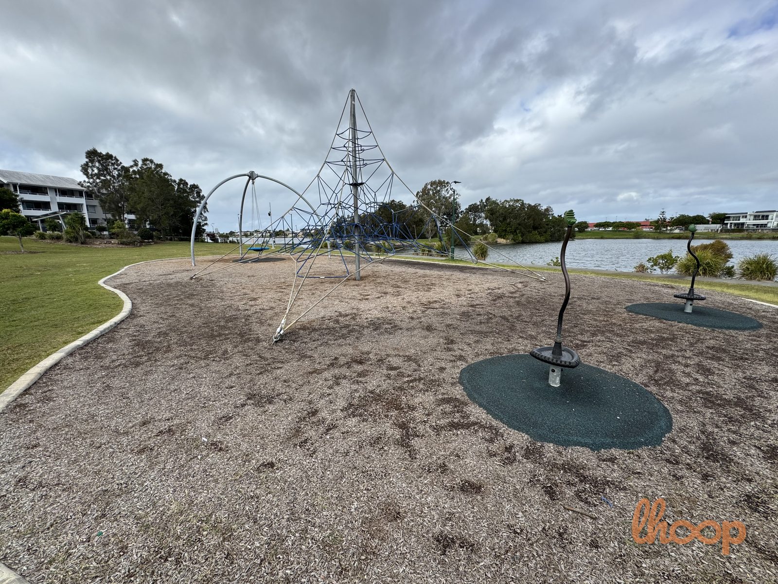 A rope climbing pyramid and two disc spinners on a soft base, with Lake Orr behind.